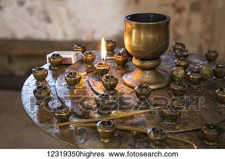Stock Photograph - Lit candle in the interior of the Church of the Saint George at Gelati Monastery; Imereti, Georgia. Fotosearch