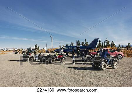 Stock Image - Locals with their trucks and ATVs surround an airplane on a gravel landing strip, Noatak, Arctic Alaska, Autumn, USA. Fotosearch