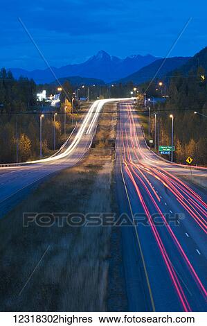 Stock Photograph - Long exposure of evening traffic on the Glenn Highway near Eagle River; Alaska, United States of America. Fotosearch