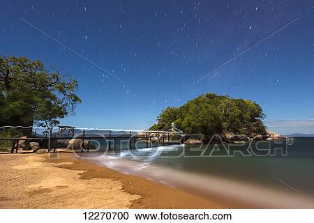 Stock Image - Long exposure photo of torch trail along small bridge going from Mumbo Island to small island for tourist's accommodation under a starry sky, Lake Malawi; Malawi. Fotosearch