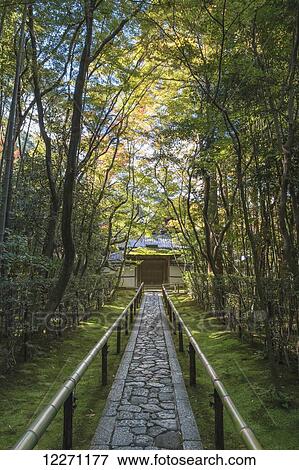 Stock Photo - Long stone pathway through the trees leading to a Japanese temple gate; Kyoto, Japan. Fotosearch