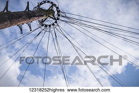 Stock Photograph - Low angle view of a telepost against a bright blue spring sky with cloud; London, England. Fotosearch
