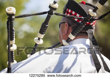 Stock Photography - Male Scottish bagpipe player, playing pipes with his back to the camera; Florida, United States of America. Fotosearch