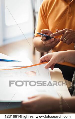 Stock Photograph - Man and woman with documents and a calculator; Regina, Saskatchewan, Canada. Fotosearch