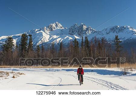 Man bicycling on frozen Rabbit Creek in the Palmer Haystack Game Refuge with Twin Peaks in the background, Southcentral Alaska, winter View Large Photo Image Stock Photograph - Man bicycling on frozen Rabbit Creek in the Palmer Haystack Game Refuge with Twin Peaks in the background, Southcentral Alaska, winter. Fotosearch