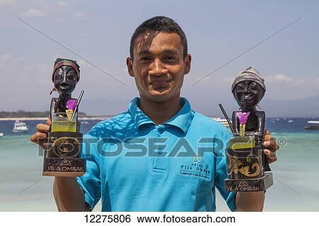Stock Photograph - Man holding exotic cocktails, Gili Trawangan, West Nusa Tenggara, Indonesia. Fotosearch