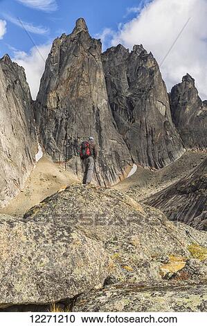 Stock Image - Man standing on a rock overlooking the granite jagged peaks of Tombstone Territorial Park; Yukon, Canada . Fotosearch
