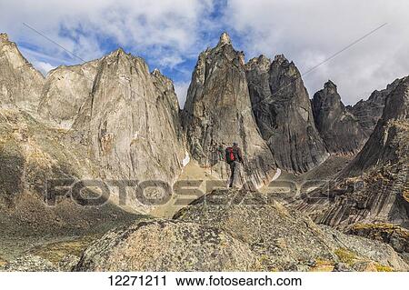 Man standing on a rock overlooking the granite jagged peaks of Tombstone Territorial Park; Yukon, Canada View Large Photo Image Stock Image - Man standing on a rock overlooking the granite jagged peaks of Tombstone Territorial Park; Yukon, Canada . Fotosearch