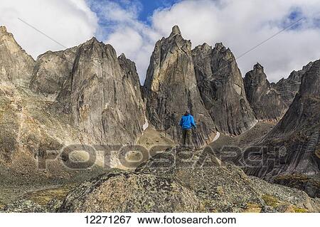 Man standing on a rock overlooking the jagged granite peaks of Tombstone Territorial Park; Yukon, Canada View Large Photo Image Stock Photo - Man standing on a rock overlooking the jagged granite peaks of Tombstone Territorial Park; Yukon, Canada . Fotosearch