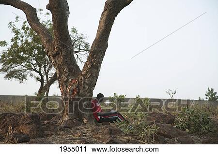 Stock Image - Medical student studying under a tree in Bamako, Mali. Fotosearch