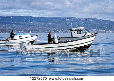 Stock Photography - Men driving their wide-body boats in Kachemak Bay near Homer Spit, Southcentral Alaska, autumn. Fotosearch