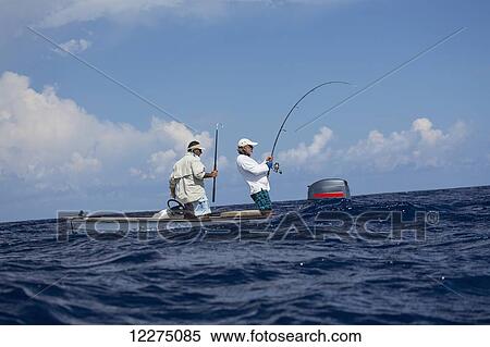 Stock Photography - Men fighting a fish from a small boat; Tahiti. Fotosearch
