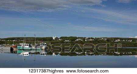 Stock Photograph - Mirror image of fishing boats and the shoreline in Inverness Harbour, Cape Breton Island; Nova Scotia, Canada. Fotosearch