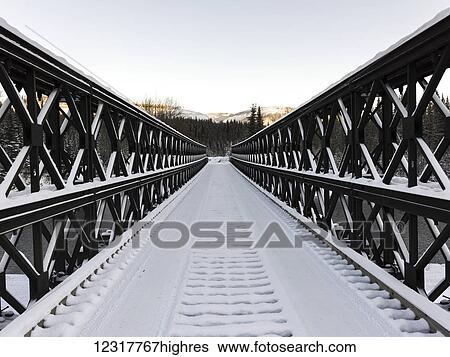 Stock Photograph - Narrow, snow covered bridge in the Northern Rockies; British Columbia, Canada. Fotosearch