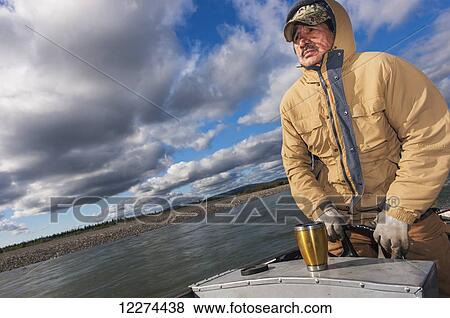 Stock Photo - Native Alaskan man driving a skiff on the Noatak River, Noatak, Arctic Alaska, USA, Fall. Fotosearch