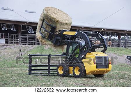 New Holland skid steer loader loading round bale into feeder; Georgia, United States of America View Large Photo Image Stock Image - New Holland skid steer loader loading round bale into feeder; Georgia, United States of America. Fotosearch