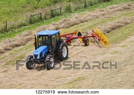Stock Photo - New Holland T5040 with H5980 wheel rake; New Holland, Pennsylvania, United States of America. Fotosearch