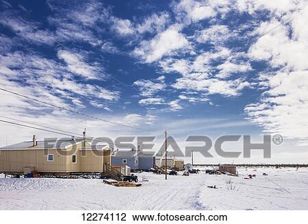 Stock Image - New housing units and power lines along a snow-covered street in Noatak, Arctic Alaska, USA, Winter. Fotosearch