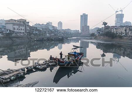 Stock Photo - Old shapowei in local fishing harbour and fishermen preparing their nets in the boat; Xiamen, Fujian Province, China. Fotosearch