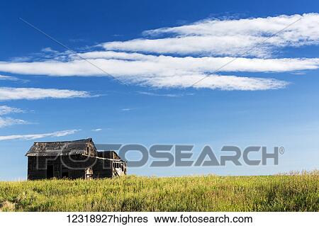 Stock Photograph - Old wooden barn in field with clouds and blue sky, South of Strathmore; Alberta, Canada. Fotosearch