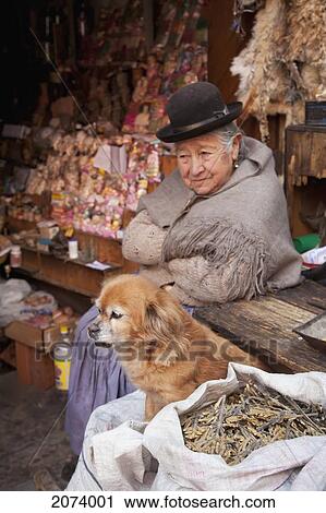 Stock Image - Ole Aymara Woman And Her Dog At The Mercado De Las Brujas (Witches' Market) On Calle Linares In La Paz., La Paz Department, Bolivia. Fotosearch