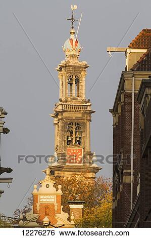 Stock Photograph - Ornate church bell tower with clock and cross; Amsterdam, Netherlands. Fotosearch
