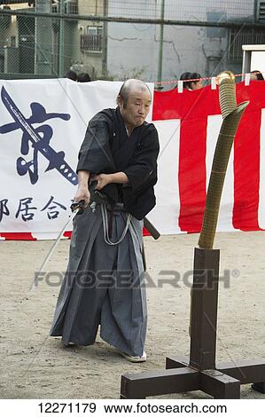 Stock Photo - Outdoor Japanese sword demonstration by older man in black kimono; Kyoto, Japan. Fotosearch