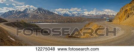 Stock Photo - Panorama of a curve in the park road as a park bus rounds the corner with Mt. McKinley towering in the background, Denali National Park, Alaska. Fotosearch