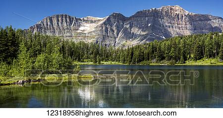 Panorama of mountain range reflecting off an alpine lake with blue sky; Banff, Alberta, Canada View Large Photo Image Stock Photograph - Panorama of mountain range reflecting off an alpine lake with blue sky; Banff, Alberta, Canada. Fotosearch