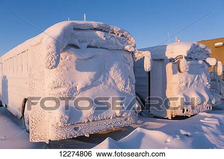 Stock Photograph - Passenger buses covered in snow after a recent Blizzard in the Prudhoe Bay Oilfield, North Slope, Arctic Alaska, Winter. Fotosearch