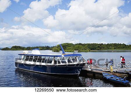 Stock Image - Passengers boarding a tour boat on a lake; Killarney, County Kerry, Ireland. Fotosearch