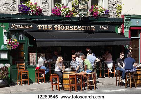 Stock Photography - Patrons sitting at barrel tables outside a pub; Kenmare, County Kerry, Ireland. Fotosearch
