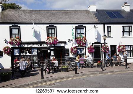 Stock Photo - Patrons sitting on an outdoor patio of an Inn; Schull, County Cork, Ireland. Fotosearch
