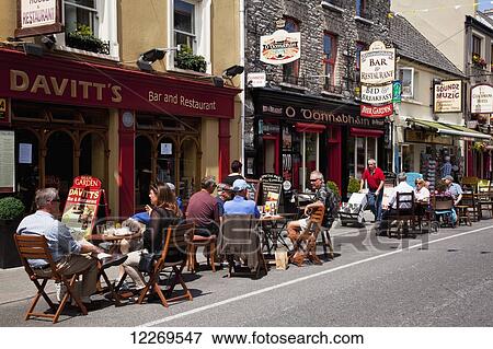 Stock Photo - Patrons sitting on outdoor patios outside restaurants; Kenmare, County Kerry, Ireland. Fotosearch