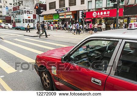 Pedestrians crossing a busy street with a red taxi waiting at the crosswalk, Central District; Hong Kong, China View Large Photo Image Stock Photo - Pedestrians crossing a busy street with a red taxi waiting at the crosswalk, Central District; Hong Kong, China. Fotosearch