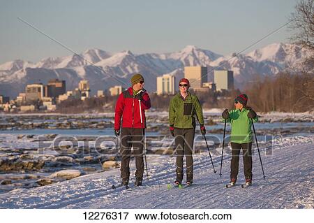 Stock Photo - People cross country skiing on the Tony Knowles Coastal Trail near Earthquake Park with Anchorage skyline in the background, Cook Inlet, Southcentral Alaska. Fotosearch