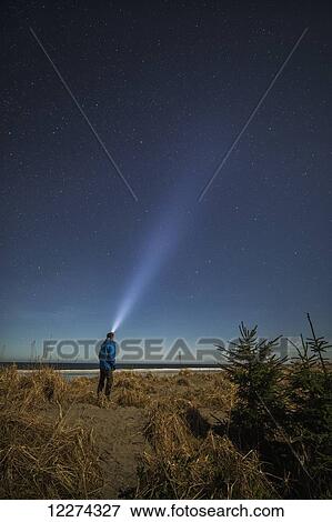 Stock Photo - Person shining his headlamp into a starry sky; Haida Gwaii, British Columbia, Canada. Fotosearch
