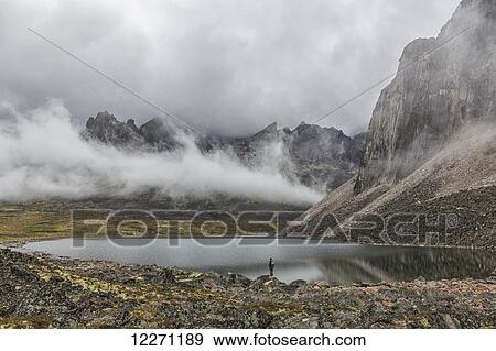 Person standing on the misty shores of Talus Lake, which lies deep within the Yukon's Tombstone Territorial Park; Yukon, Canada View Large Photo Image Stock Photo - Person standing on the misty shores of Talus Lake, which lies deep within the Yukon's Tombstone Territorial Park; Yukon, Canada. Fotosearch