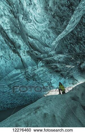 Stock Image - Person standing under the Vatnajorkull ice cap in a large ice cave, South central Iceland; Iceland. Fotosearch
