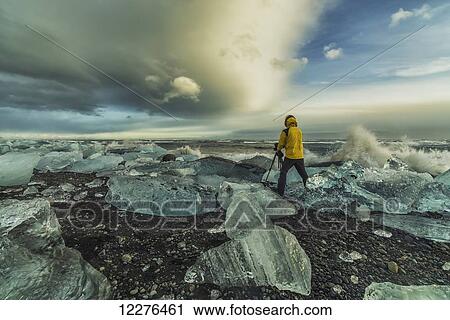 Stock Image - Photographer taking pictures along the Southern shoreline of Iceland with large chunks of ice laying about; Iceland. Fotosearch
