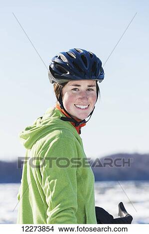 Picture - Portrait of a smiling young woman wearing a black bicycle helmet, Anchorage, Southcentral Alaska, Winter, USA. Fotosearch