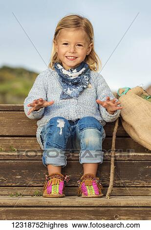 Stock Photograph - Portrait of a young girl sitting on wooden steps; Tarifa, Cadiz, Andalusia, Spain. Fotosearch