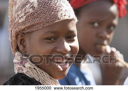 Stock Image - Portrait of a young girls cleaning teeth with stick in Bamako, Mali. Fotosearch