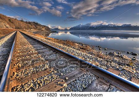 Stock Image - Railroad tracks along Turnagain Arm and the Seward Highway near Anchorage, Southcentral Alaska, Spring, HDR. Fotosearch
