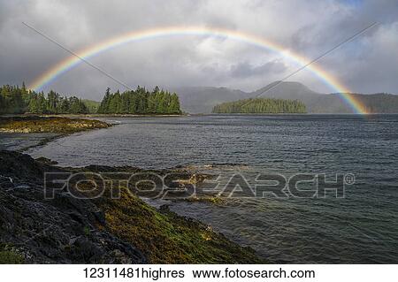 Stock Photograph - Rainbow forms over the ocean during a wind and rain storm; Haida Gwaii, British Columbia, Canada. Fotosearch