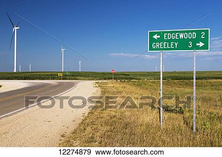 Stock Photo - Road sign indicating miles to Edgewood and Greeley Iowa with wind turbines from the Elk Wind Energy Farm in background; Iowa, United States of America. Fotosearch