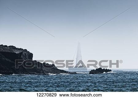 Rock on the rugged coastline with a sailboat in the fog; Tarifa, Cadiz, Andalusia, Spain View Large Photo Image Stock Photo - Rock on the rugged coastline with a sailboat in the fog; Tarifa, Cadiz, Andalusia, Spain. Fotosearch