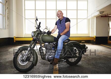 Stock Photograph - Royal Enfield Cafe Cruiser and it's owner in parking garage; Toronto, Ontario, Canada. Fotosearch