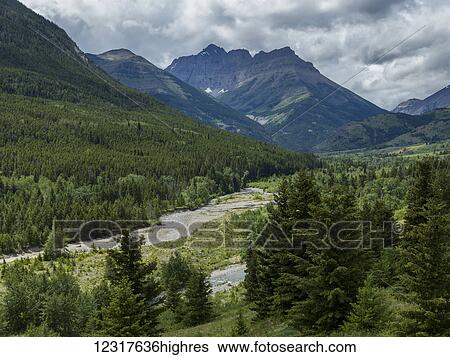Stock Photograph - Rugged mountain peaks and green forested landscape, Waterton Lakes National Park; Alberta, Canada. Fotosearch
