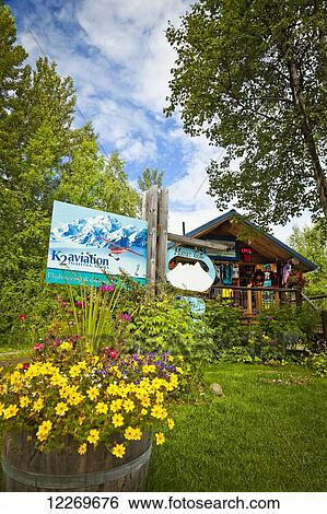 Stock Photograph - Rustic log cabin building of K2 Aviation surrounded by flower pots, Talkeetna, Southcentral Alaska, Summer.. Fotosearch